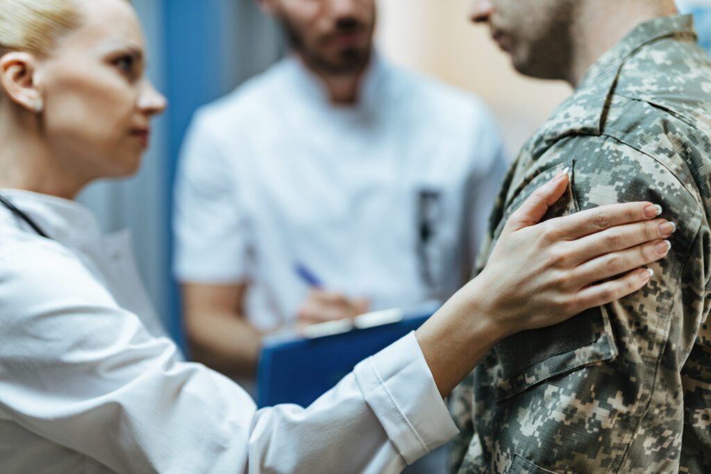 Close-up of a soldier being consoled by healthcare workers at clinic.